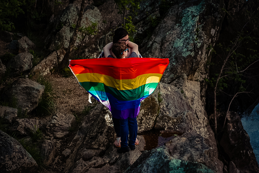 Two brides to be posing with a pride flag during their Great Falls engagement photos by Potok's World Photography, engagement photographers in Maryland