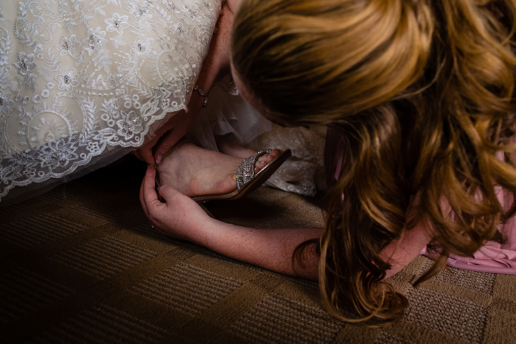 Maid of honor helping bride with shoes atOmni Shoreham DC wedding by DC wedding photographers Potok's World Photography