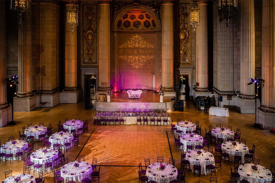 Wedding decor at the Mellow Auditorium with elements of gold, pink and purple. Tall cylinder vases with floating candles add an element of elegance by DC wedding photographers Potok's World Photography