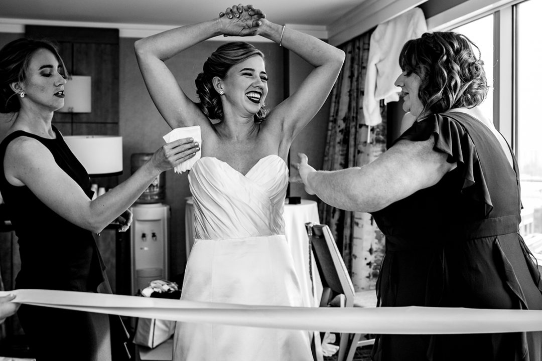 Bride wearing wedding dress and is being helped by her maid of honor at the Westin in Old Town Alexandria by DC wedding photographers of Potok's World Photography