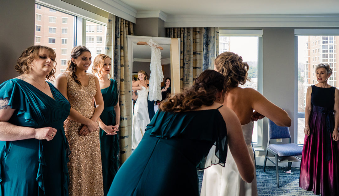 Bride getting into her wedding dress with her bridal party at the Westin Old Town before Carlyle Club Alexandria reception by DC wedding photographers of Potok's World Photography