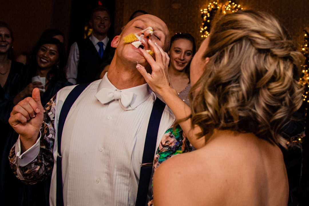 Bride smashes piece of cake during cake cutting at the Carlyle Club Alexandria by DC wedding photographers Potok's World Photography