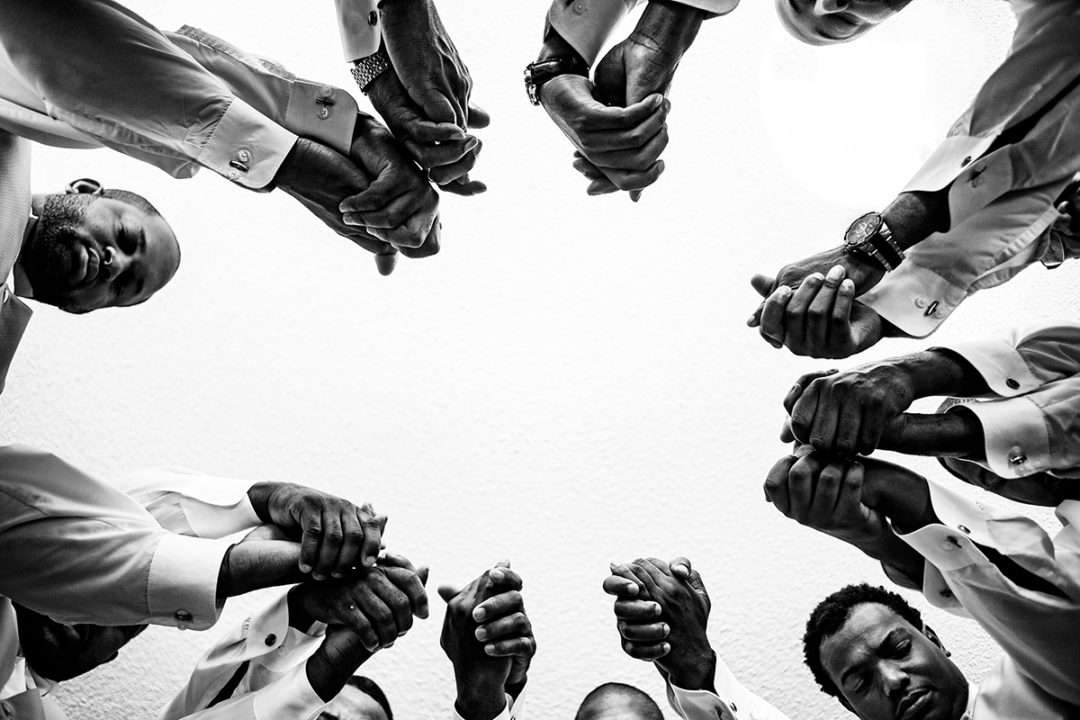 Documentary wedding photography of groom and groomsmen praying before the ceremony in Baltimore by Pete Martin of Potok’s World Photography, Washington DC wedding photographers