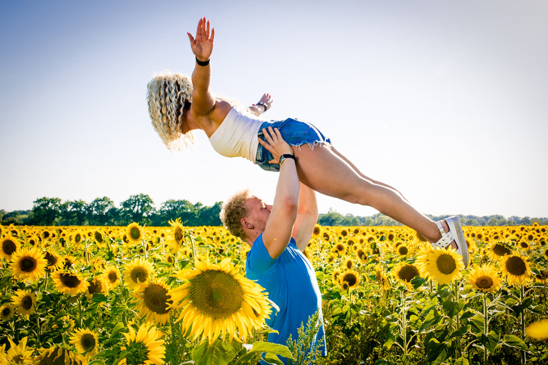 Couple doing acrobatic poses during sunflower field during engagement photos by DC wedding photographers of Potok's World photography