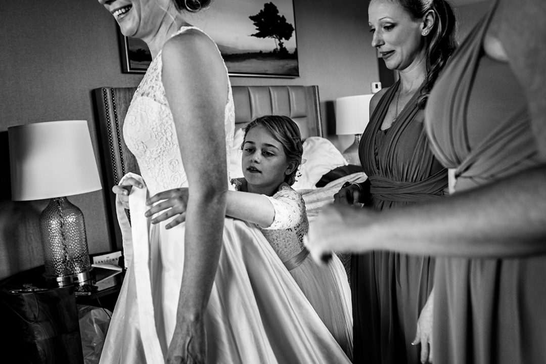 Bride getting into bridal dress with her bridesmaids at Lansdowne Resort and Spa in Leesburg before her Vanish Brewery wedding by DC wedding photographers Potok's World Photography