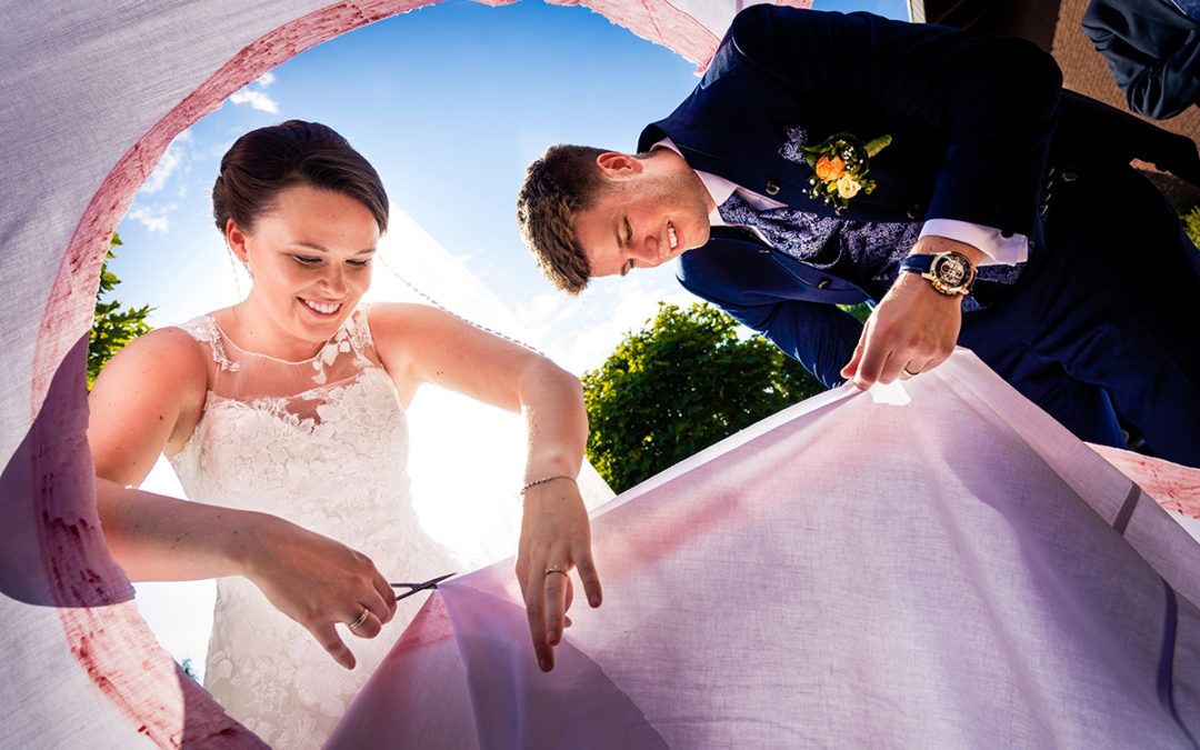 Bride and groom cutting a sheet together as part of a wedding tradition in northern Germany by Potok's World Photography