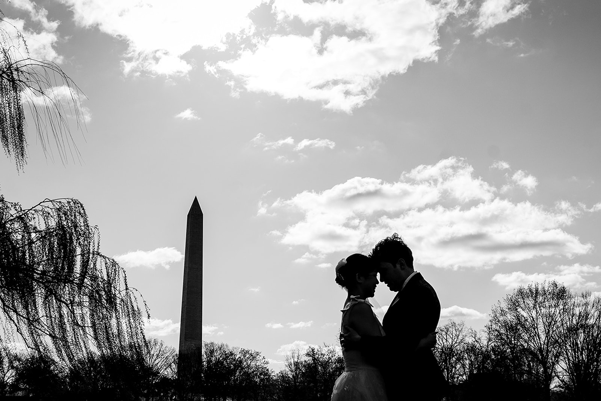 Bride and groom are silhouetted with the Washington Monument in the background at the Constitution Gardens by Potok's World Photography