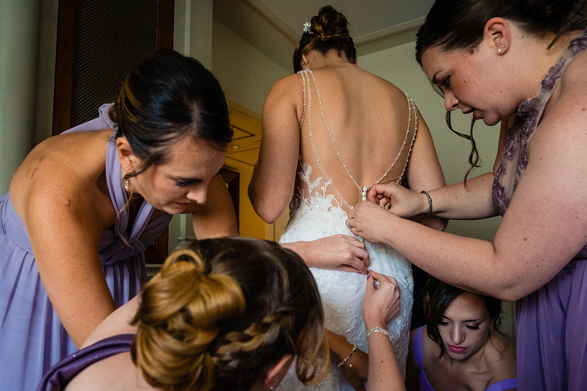 Bride getting ready at the St. Regis in Washington DC by getting into her wedding dress before her ceremony by Potok's World Photography
